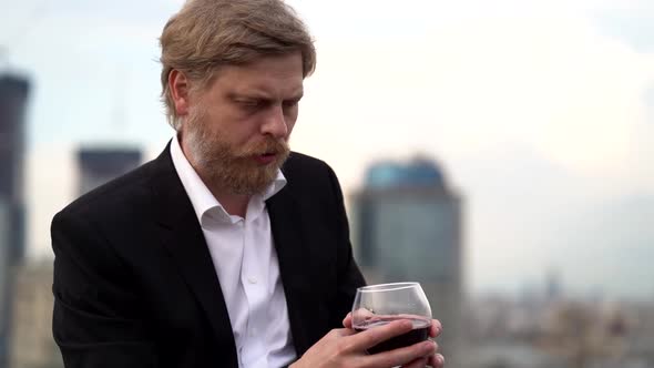Bearded Sad Man Is Drinking Wine Alone on Roof in City, Abandoned and Desperate alt