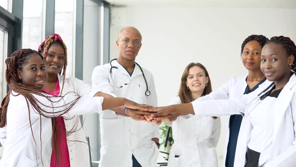 A Team of Doctors Including Women and Men of Different Nationalities Make a Gesture of Unity alt