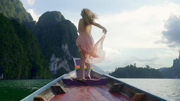 Girl with Curly Hair Spreads Dress on the Edge of the Canoe alt