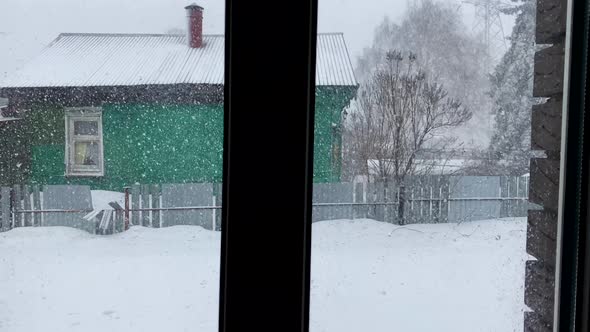 Wooden russian house in winter. View from the window. Snowing. Fir-tree. Russian village. Christmas