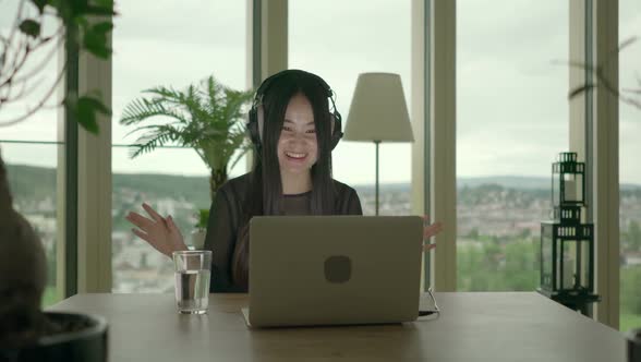Young Asian Female Listening Music on Laptop Computer at Home alt