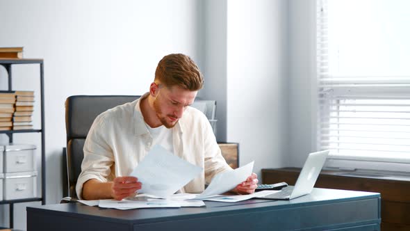 Depressed company manager looks at sheets of paper reports alt