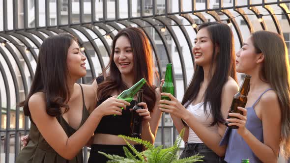 Group of happy Asian girls celebrating with drink bottle at a party