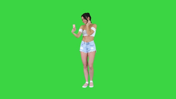 Beautiful Young Woman Doing Selfie on a Green Screen, Chroma Key. alt