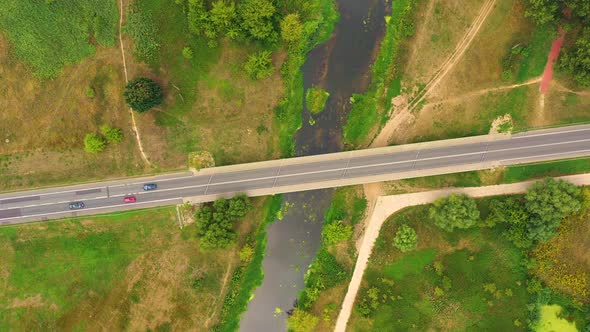 aerial drone shoot. Flying over a bridge green field in a rural landscape. Top view of trees in fore alt
