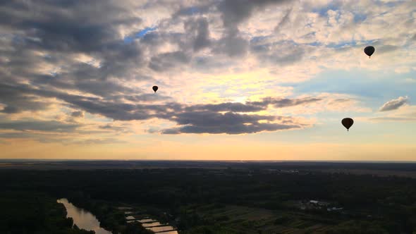Silhouettes of Hot Air Balloons Flying Over Countryside Near Small European City at Summer Sunset in alt