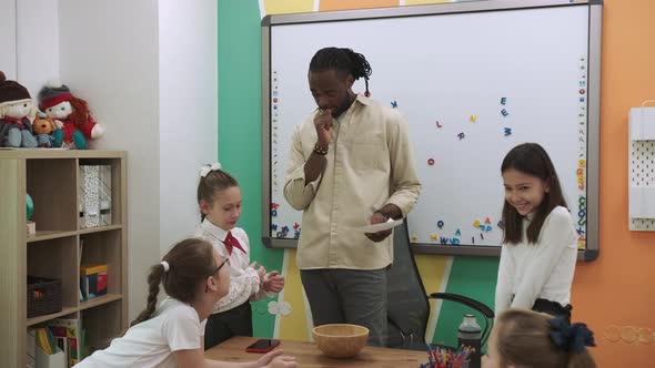 An African American Teacher Teaches a Group of Children English By Playing with Them