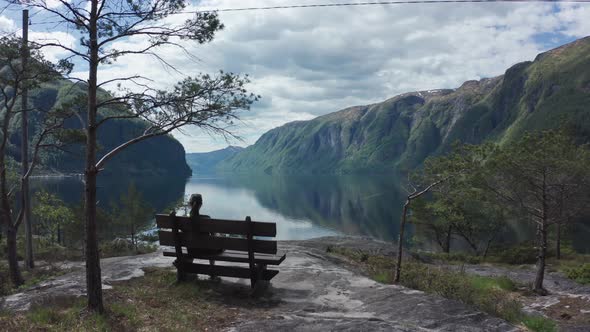 Woman relaxing on bench viewing picture perfect Sorfjorden Fjord Norway - Stanghelle western Norway alt