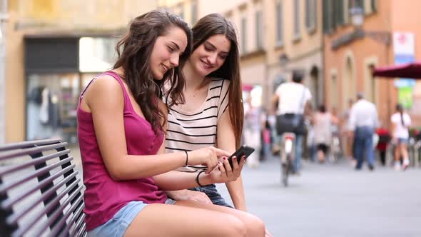 Two girls looking at a smartphone alt