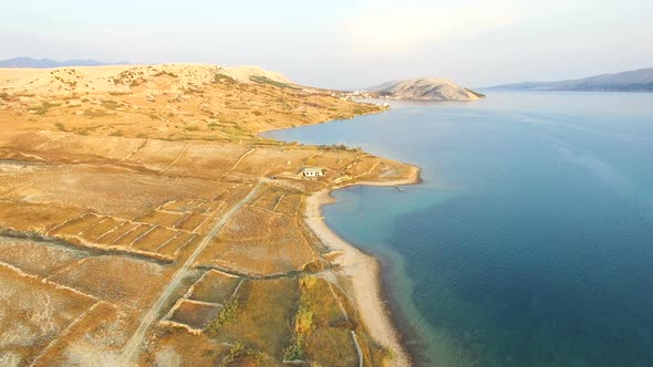 Flying above isolated house in yellow grass of Pag island, Croatia alt