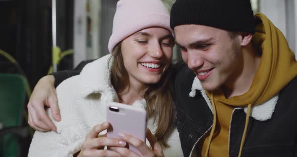 Handsome Guy Embracing His Lovely Girlfriend While They Looking at Smartphone Screen. Happy Young alt