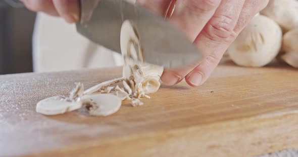 Close up of a chef knife slicing champignon mushrooms alt