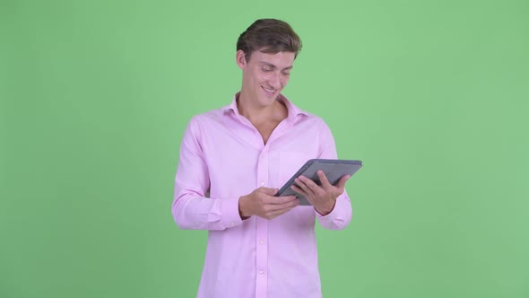 Happy Young Handsome Businessman Thinking While Using Digital Tablet alt