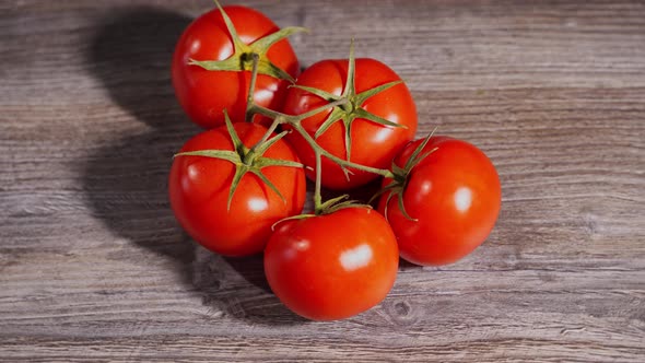 Beautiful Red Tomatoes on a Branch Lie on a Gray Wooden Table alt