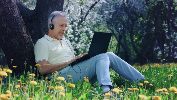 An Elderly Whitehaired Man with a Laptop is Excited and Rejoices in an Online Victory or Good News