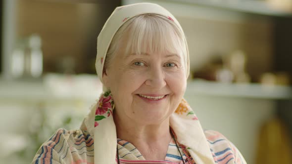 Portrait of Babushka Senior Woman Cooking and Smiling at the Kitchen alt