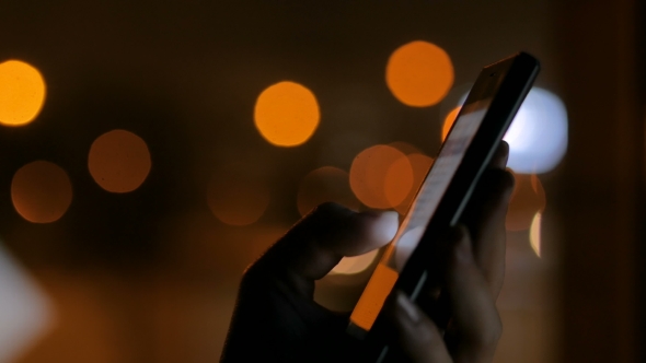 Woman Using Vertical Black Smartphone at Night
