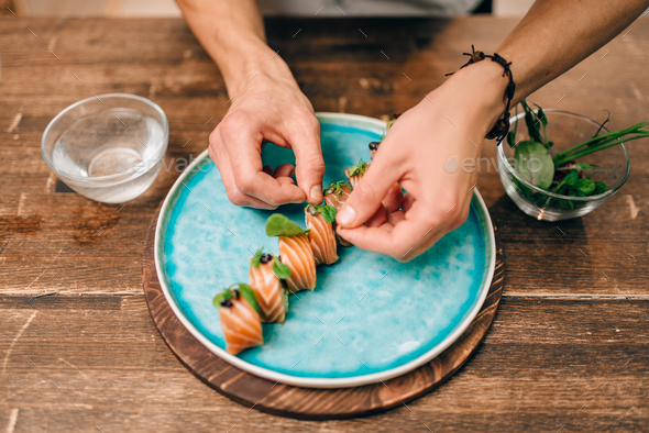 Male person cooking sushi rolls with salmon - Stock Photo - Images