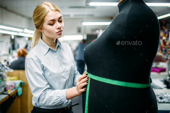 Clothes designer measures a dress on mannequin - Stock Photo - Images
