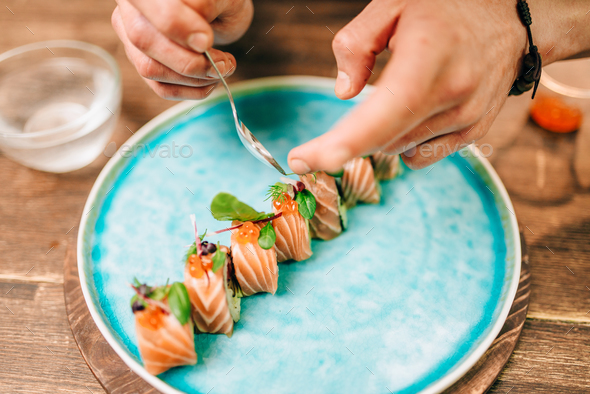 Male person cooking sushi rolls with salmon - Stock Photo - Images