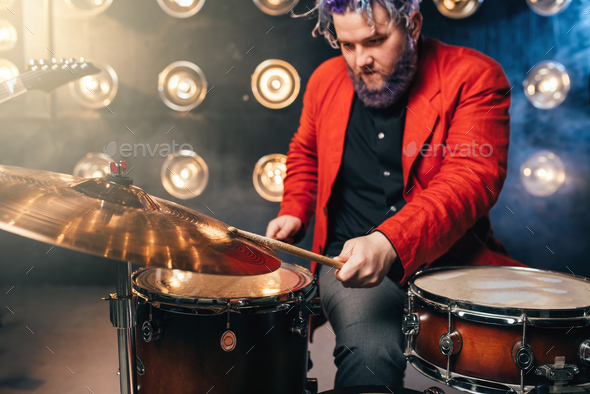Bearded drummer in red suit, performing on stage - Stock Photo - Images
