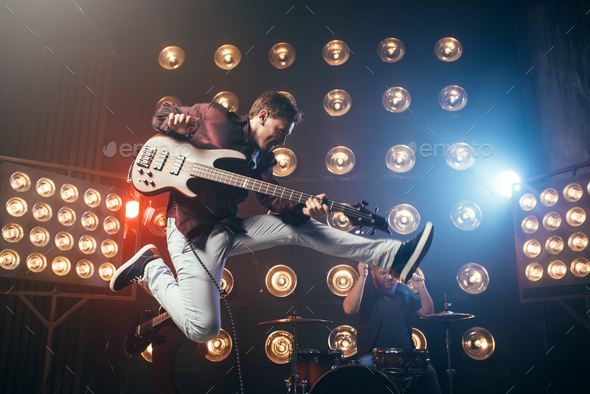 Guitarist plays on bas-guitar, snapshot in a jump - Stock Photo - Images