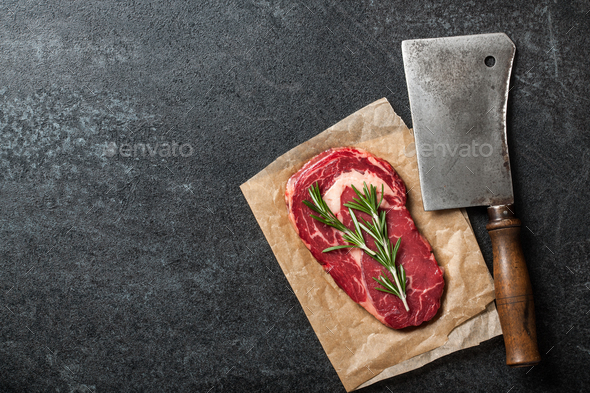 Raw rib eye steak and butcher knife on blackboard - Stock Photo - Images