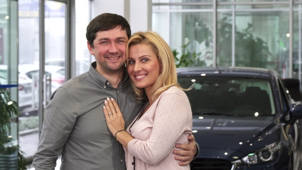 Happy Couple Laughing High Fiving After Buying a New Car at the Dealership alt