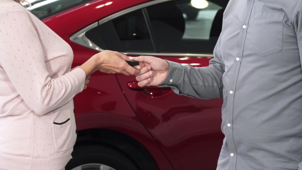 Cropped Shot of a Woman Receiving Keys To Her New Auto at the Dealership alt