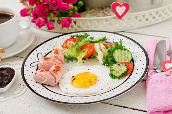 Breakfast on Valentine's Day - fried egg in the shape of a heart, toasts, sausage - Stock Photo - Images