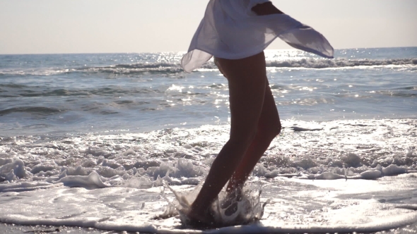 Feet of Woman in Bikini and Shirt Running on the Sea Waves at Sunrise. Young Beautiful Girl Jogging alt