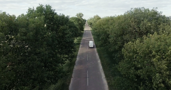 White Car Moving Fast on Two Lane Road in Forest