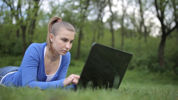 College Student Lying Down On The Grass Working On Laptop At Campus alt