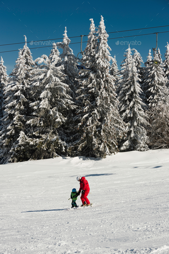 Little boy and ski trainer on mountain