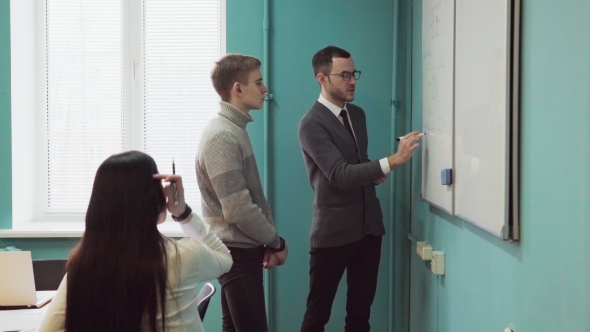 Teacher Explains Something on a Whiteboard To Students