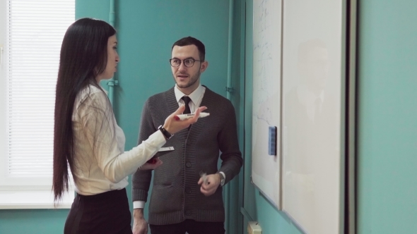 Man and Woman Conduct a Business Meeting Near Whiteboard alt