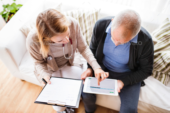 Health visitor and a senior man with tablet during home visit. - Stock Photo - Images