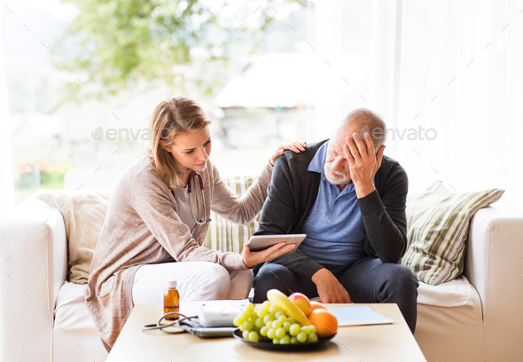 Health visitor and a senior man with tablet during home visit. - Stock Photo - Images