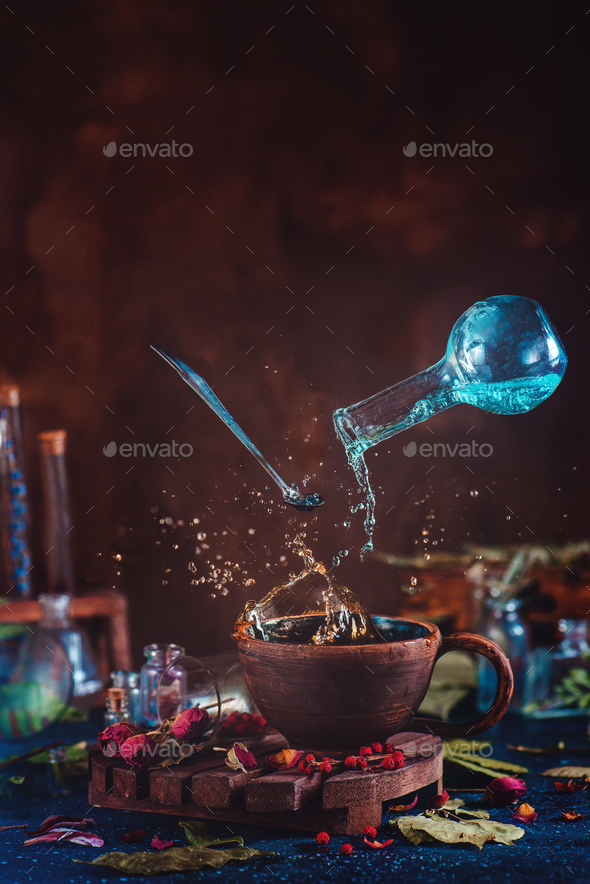 Flying potion bottle with pouring liquid in a magical still life. Brewing magical tea. - Stock Photo - Images