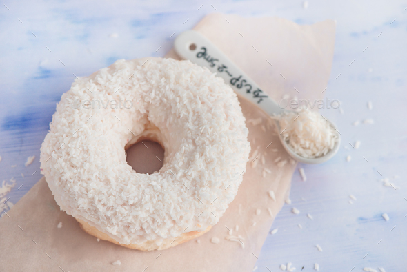 Close-up of a white donut with coconut topping on a light background. High key food photography. - Stock Photo - Images