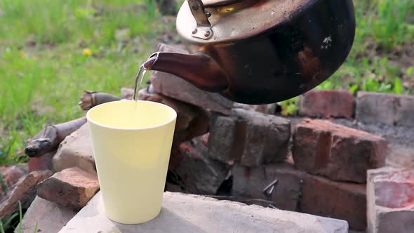 Pouring tea in white cup grunge teapot picnic mood