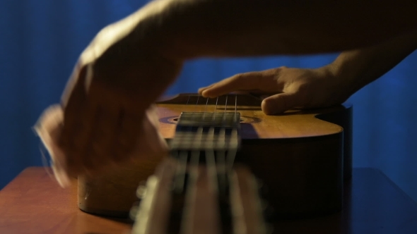 Purposeful Man Rubs Body of His Old Guitar From Dust alt