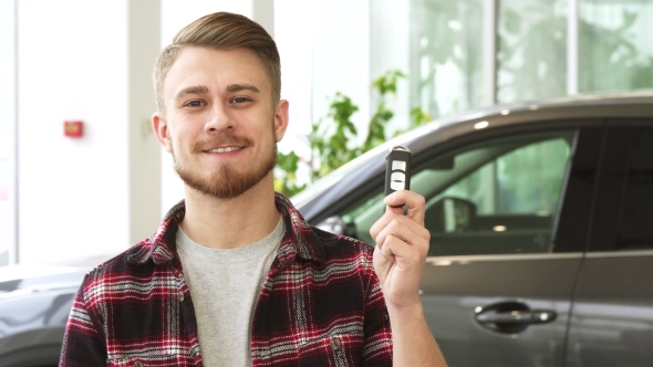Attractive Young Man Smiling Holding Car Keys Posing at the Automotive Dealership alt