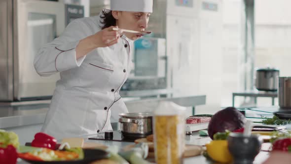 Female Chef Cooking Gourmet Soup Recipe and Doing Taste Test alt