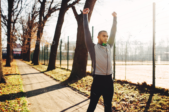 Sportsman warming up before run in autumn park - Stock Photo - Images