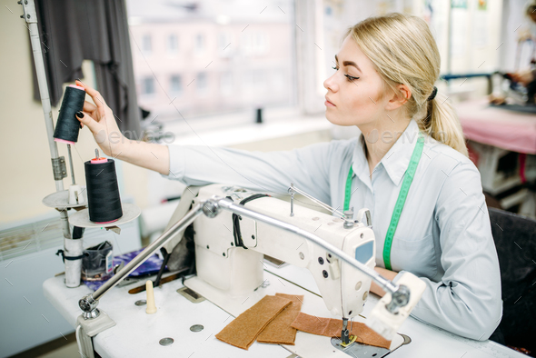 Female dressmaker sews on serger machine - Stock Photo - Images