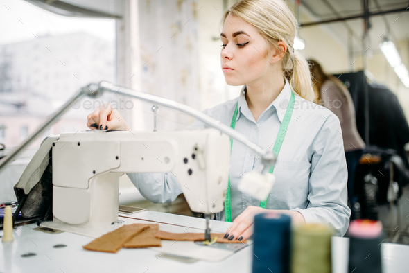 Female dressmaker sews on serger machine - Stock Photo - Images