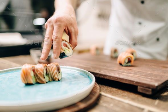 Male person cooking sushi rolls on wooden table - Stock Photo - Images