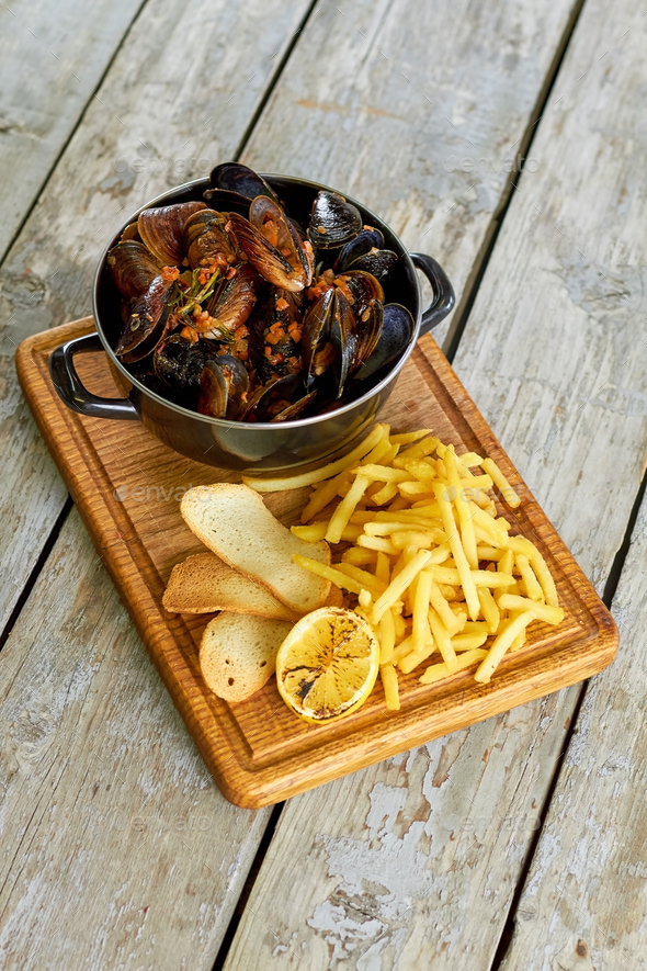 Top view saucepan with mussels and side dish. Stock Photo by