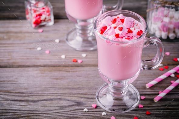 Pink hot milk with marshmallow and sugar hearts in a glass mug for ...